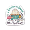 A die-cut sticker featuring a cupcake surrounded by sewing-themed items and the text 'I Deserve a Snack After That Seam!' on a plain white background.