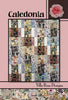 Caledonia quilt pattern cover with side-framed blocks in black, cream, rust, and blue prints